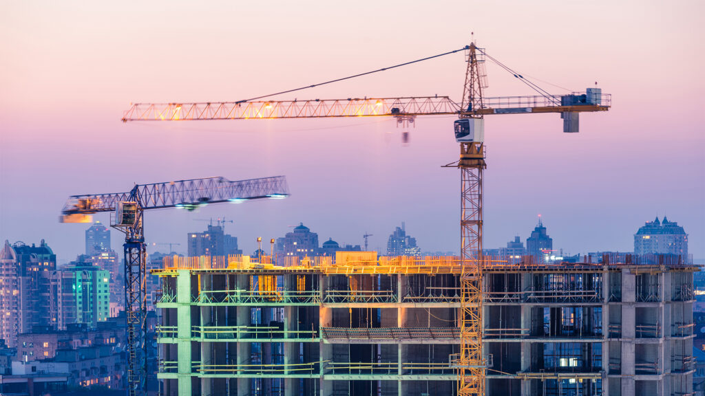 Construction of office building on purple sunset with two cranes